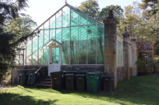 Image #3. Edgerton Park greenhouse housing the Sarah T. Crosby Conservatory and the  G.R.O.W.E.R.S. program. Featuring tropical plants and a main entrance constructed from cut  stone with crenelated detailing. 